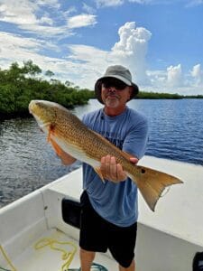 man holding a large redfish on a boat in fort myers fishing charters