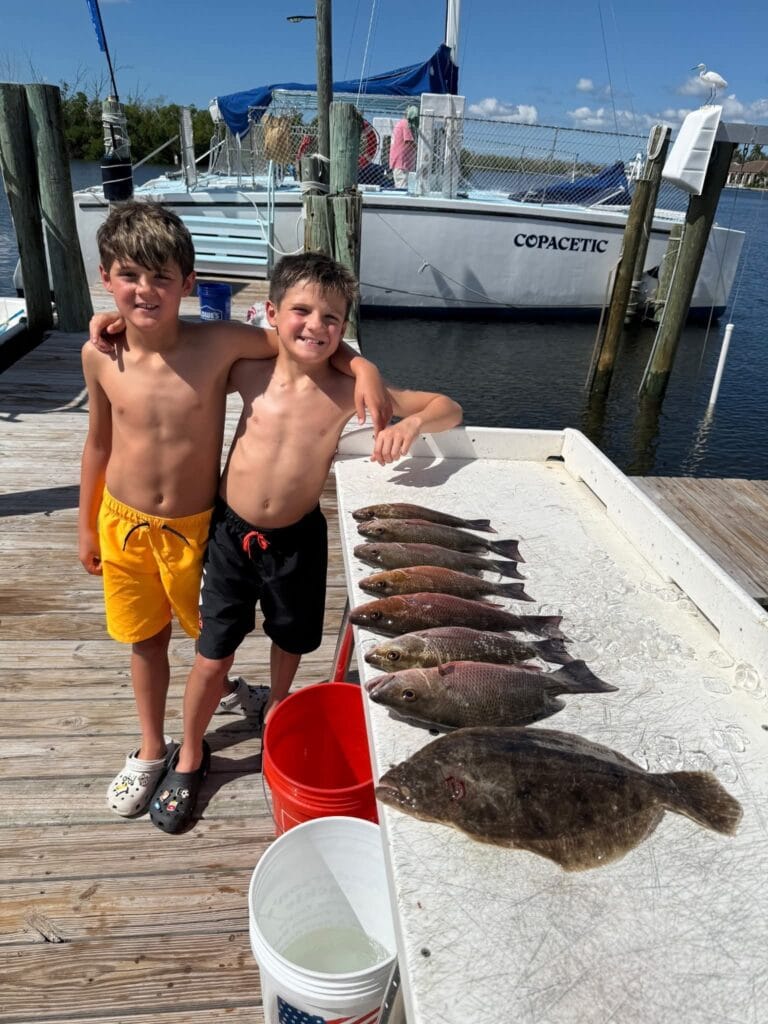 boys standing next to a table full of redfish that they caught on their back bay fishing charter with Luck o' The Irish Fishing Charters