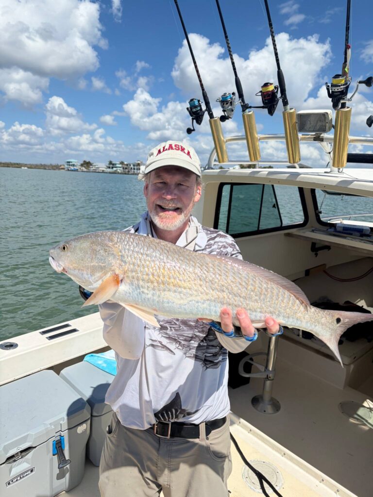 a man holding a beautiful redfish that he caught back bay with luck o' the irish fishing charters