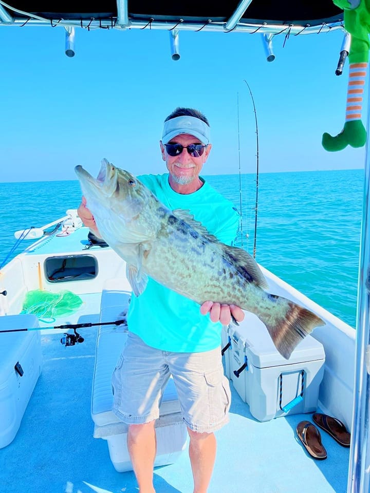 Captain Kenny holding a grouper that he caught while fishing off the shoreline of Fort Myers, FL