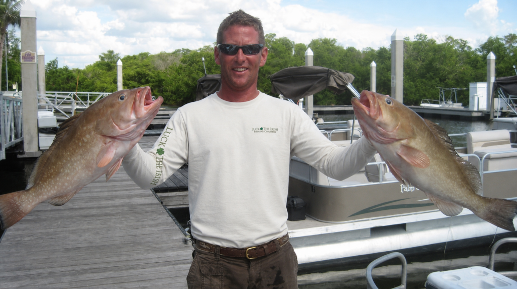 Captain Rich holding grouper after a long day of fishing with luck o' the irish fishing charters