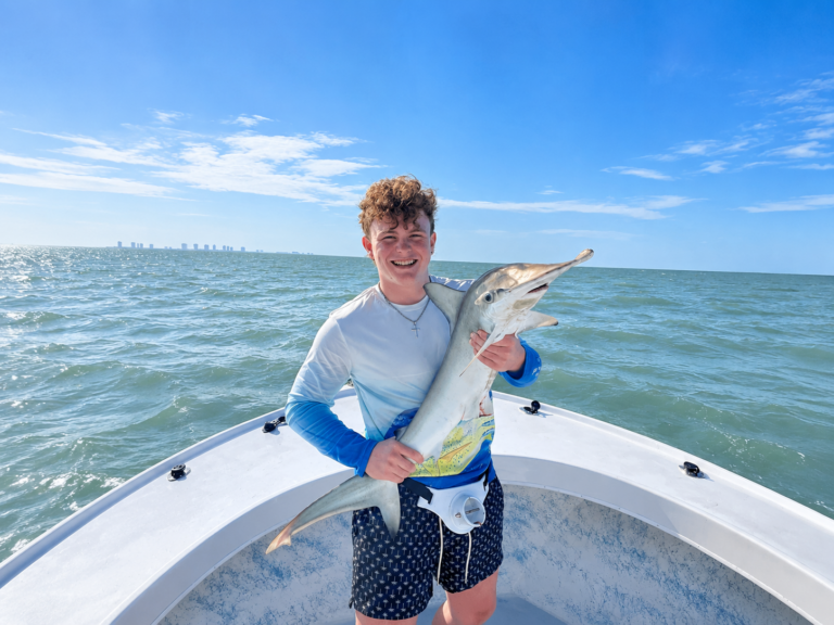 man holding a shark on a shark fishing charter with luck o' the irish fishing charters