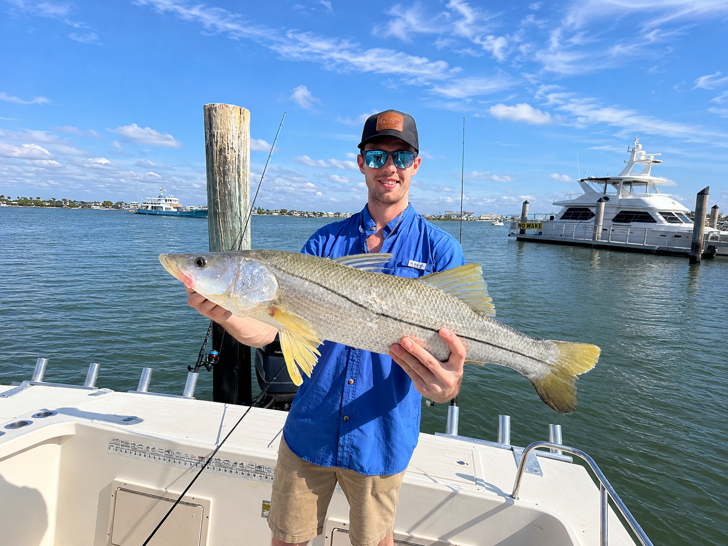 a man holding a beautiful snook aboard a 24 foot parker in the back bay of fort myers, fl