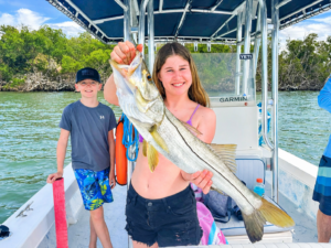 a girl holding a nice snook that she caught on a 27 foot skiff in fort myers, florida