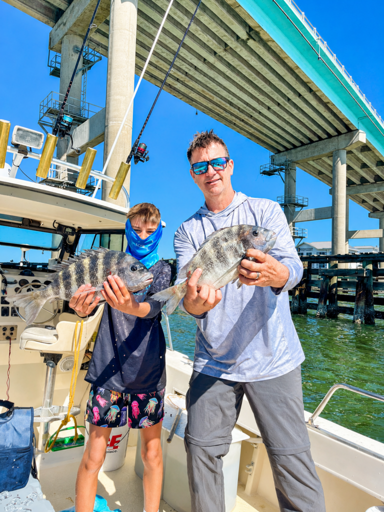 a man and his son standing on a 24 foot parker holding sheepshead that they caught under the Fort myers beach bridge