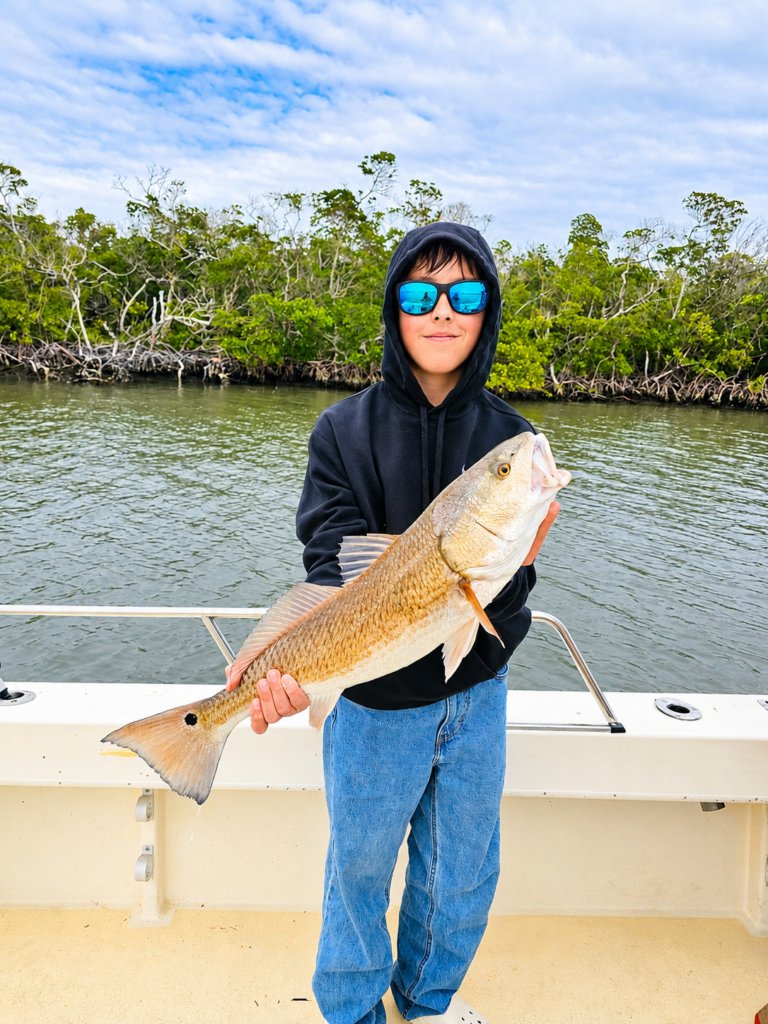 a boy in the back bay of fort myers, fl on a 24 foot parker holding a redfish
