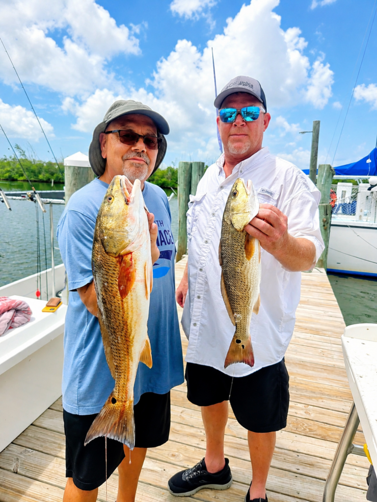 2 men each holding a redfish